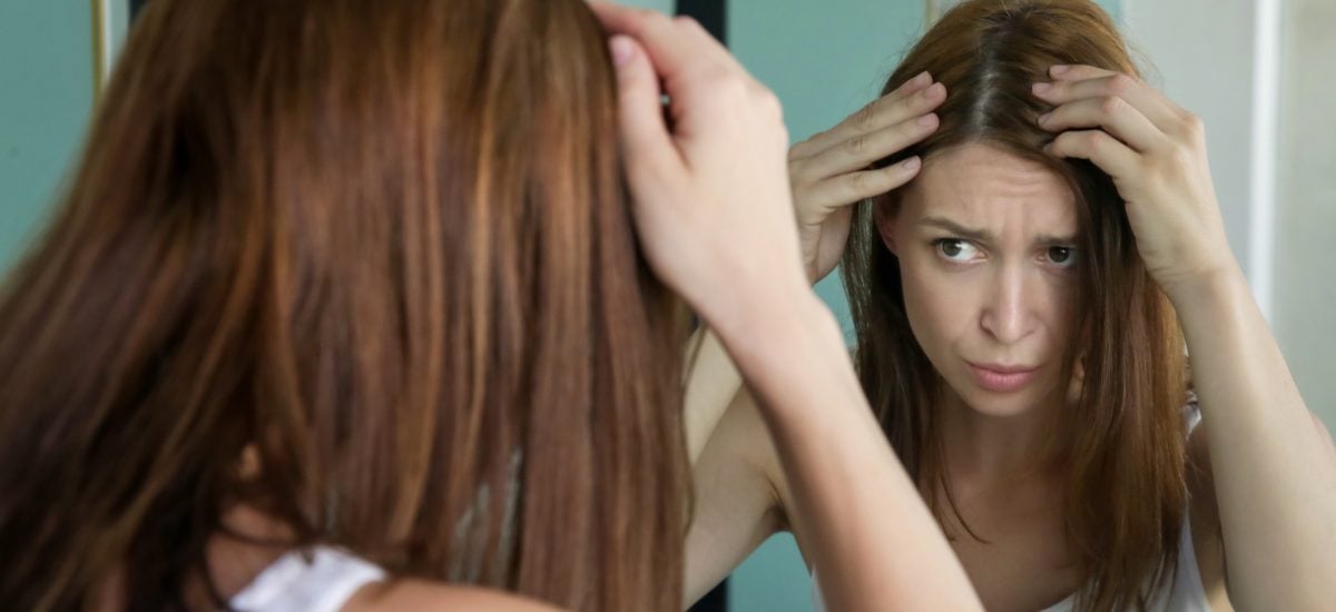 Žena si kontroluje vlasy pred zrkadlom