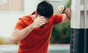 Muž trpiaci závratom opierajúci sa o stenu