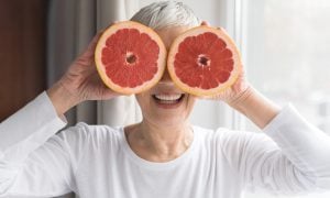 Seniorka držiaca grepy na očiach
