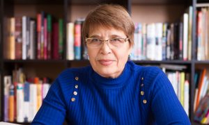 Šťastná seniorka v knižnici s knihou