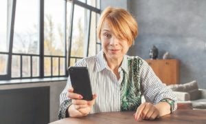 Šokovaná žena s mobilným telefónom v ruke