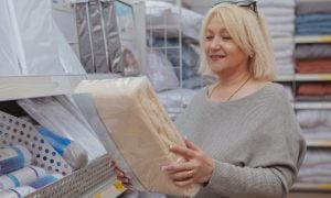 Zrelá žena s balíkom posteľných obliečok