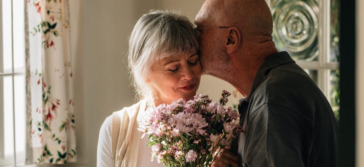 starší pár oslavuje výročie, muž dal svojej žene kyticu kvetov