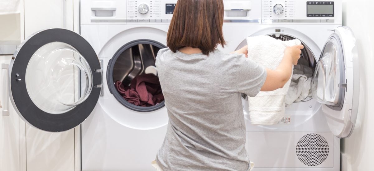 Žena dáva veci do práčky na pranie