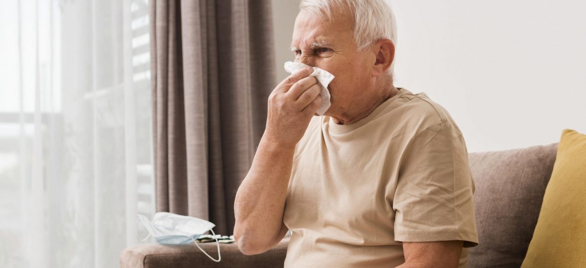 Starší pán má alergiu a fúka si nos.