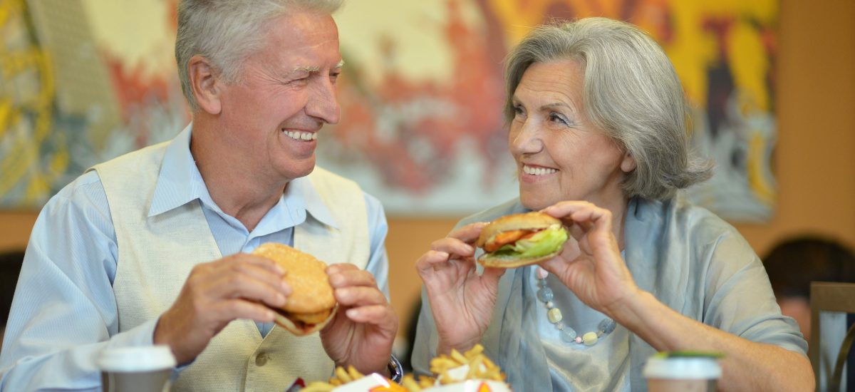 starší muž a žena jedia fastfood