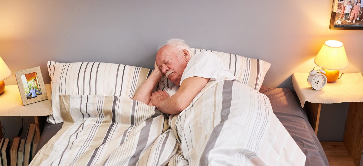 starší pán spí v posteli