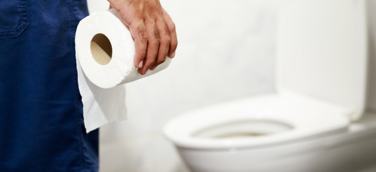 muž drží v ruke toaletný papier a smeruje k záchodu