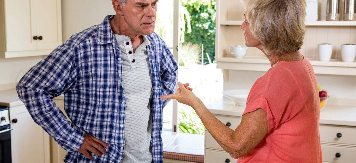 staršia žena stojí v kuchyni a háda sa s mužom