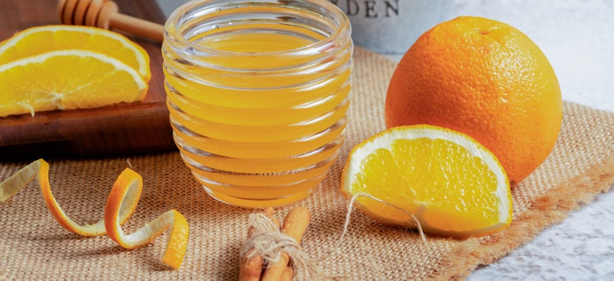 pomarančový sirup v nádobe a pomaranče