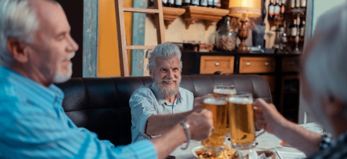 starší muži si pripíjajú s pivom