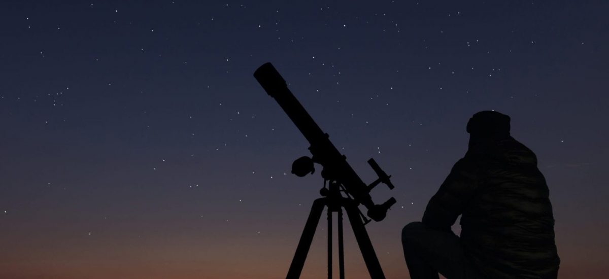 muž pozorujúci oblohu astronomickým ďalekohľadom