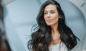 Krásna tmavovlasá žena sa díva do zrkadla