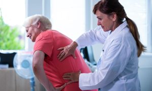 doktorka vyšetruje ženu s bolesťou chrbta