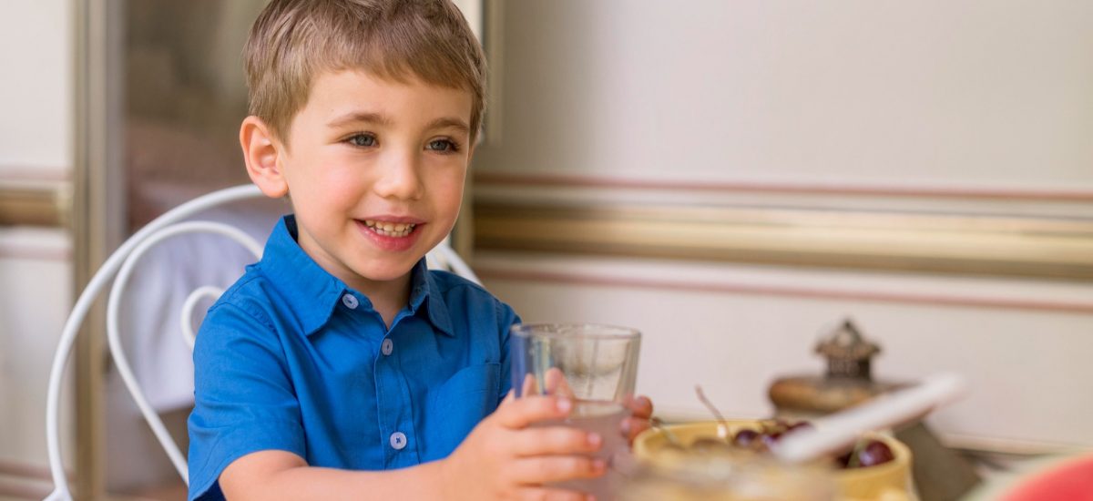 malý chlapec s pohárom vody ako letný pitný režim