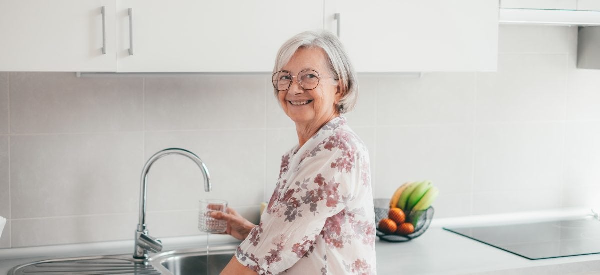 staršia žena v kuchyni ije vodu