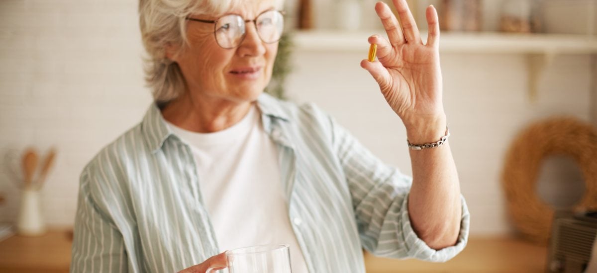 staršia žena drží v ruke tabletku