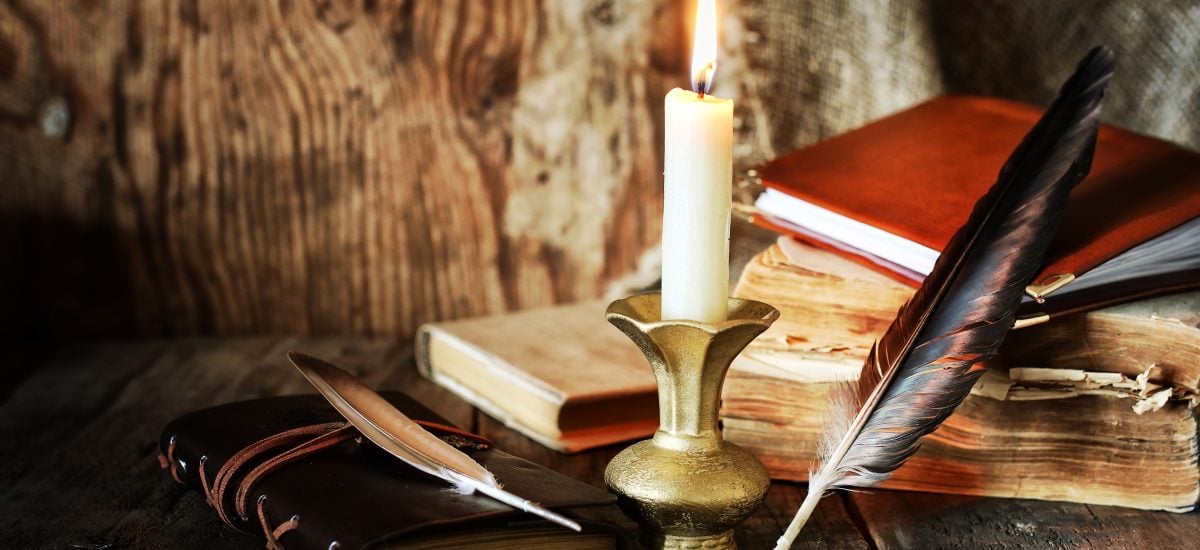 knihy, sviečka a brko na stole
