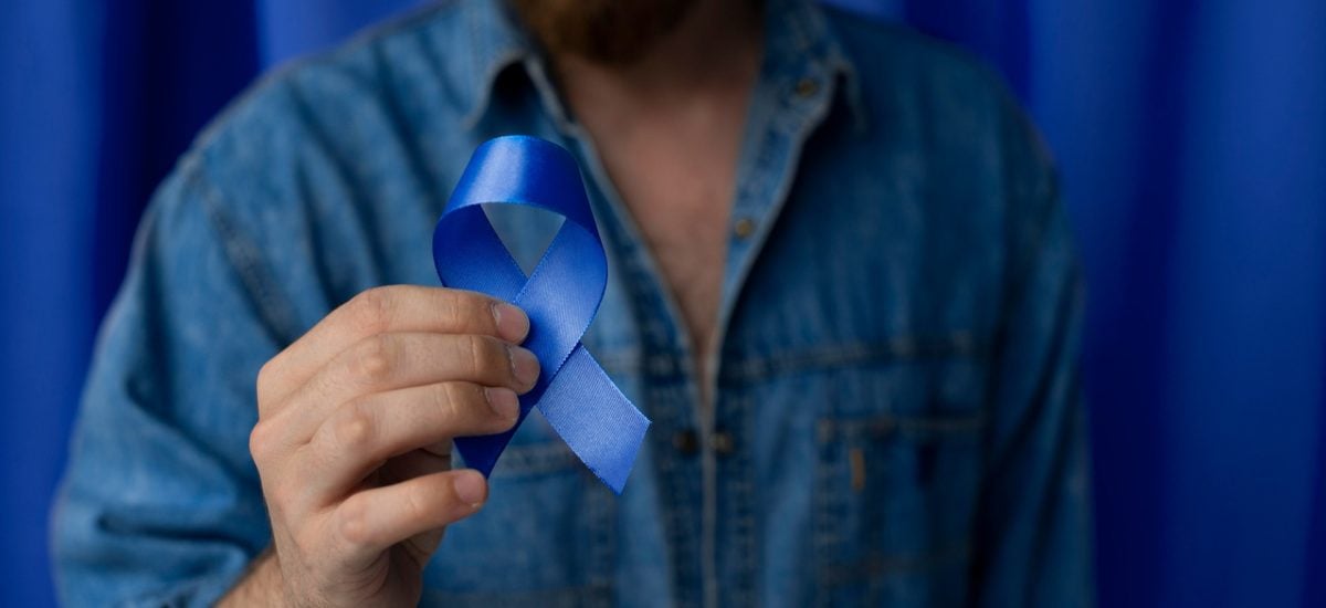 muž drží modrú stuhu, mesiac prevencie rakoviny