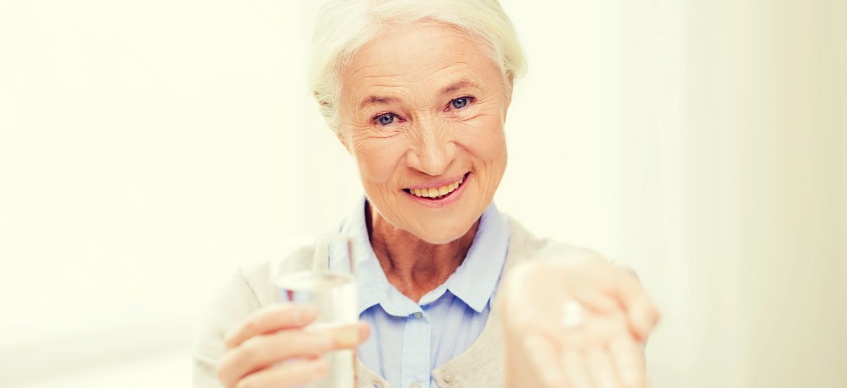staršia pani drží v ruke pohár a tabletku