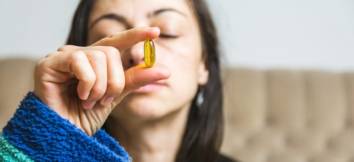 žena skúma význam vitamínu D v žltej kapsule