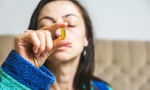 žena skúma význam vitamínu D v žltej kapsule