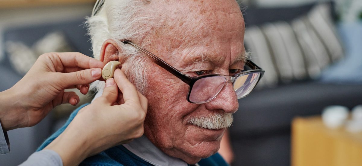 starší muž dostáva načúvací prístroj