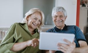 usmievajúci sa manželia pozerajú na tablet