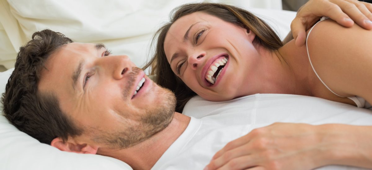 usmiavajúci sa muž a žena ležia v posteli