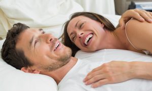 usmiavajúci sa muž a žena ležia v posteli