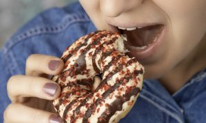 žena odhrýzajúca z donutu