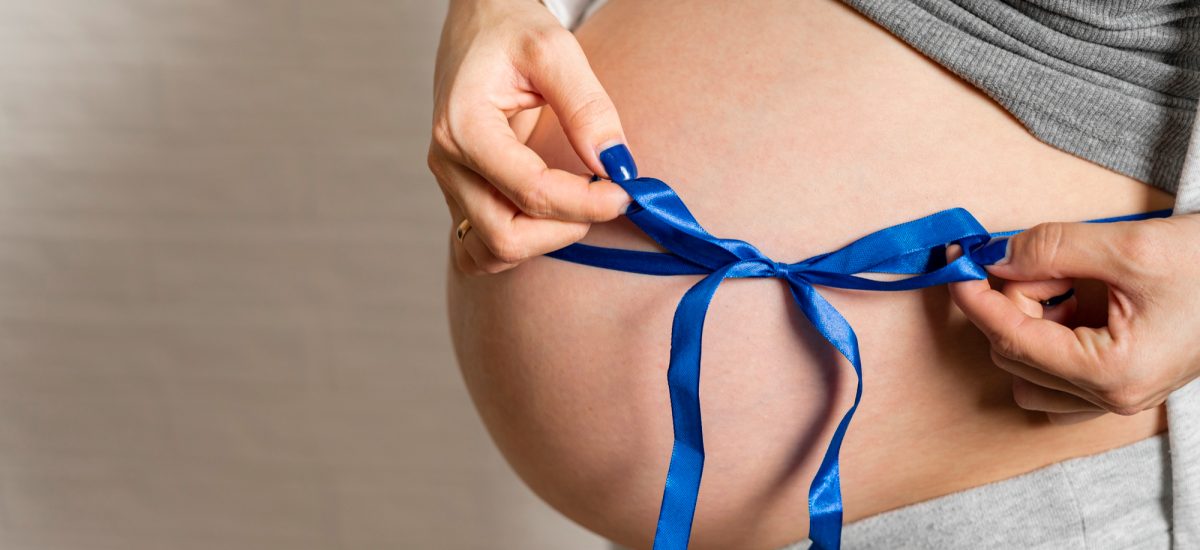 emócie ženy a tehotenské bruško previazané modrou mašľou