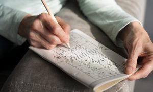 muž rieši logické hry ako sudoku