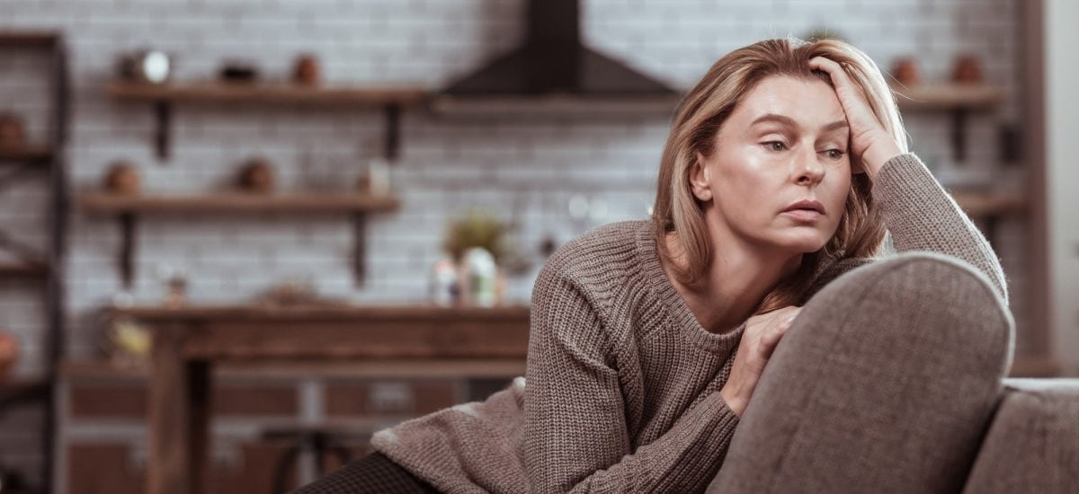 ženu sediacu na pohovke trápi zimná malátnosť a únava