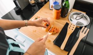 žena krája paradajku a používa kuchynské pomôcky