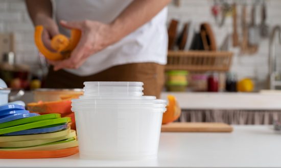 muž v kuchyni pripravuje jedlo na uskladnenie v plastových nádobách